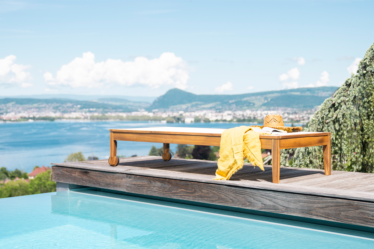 Bain de soleil NAVEEN en bois massif pr�s d'une piscine avec vue sur un lac.