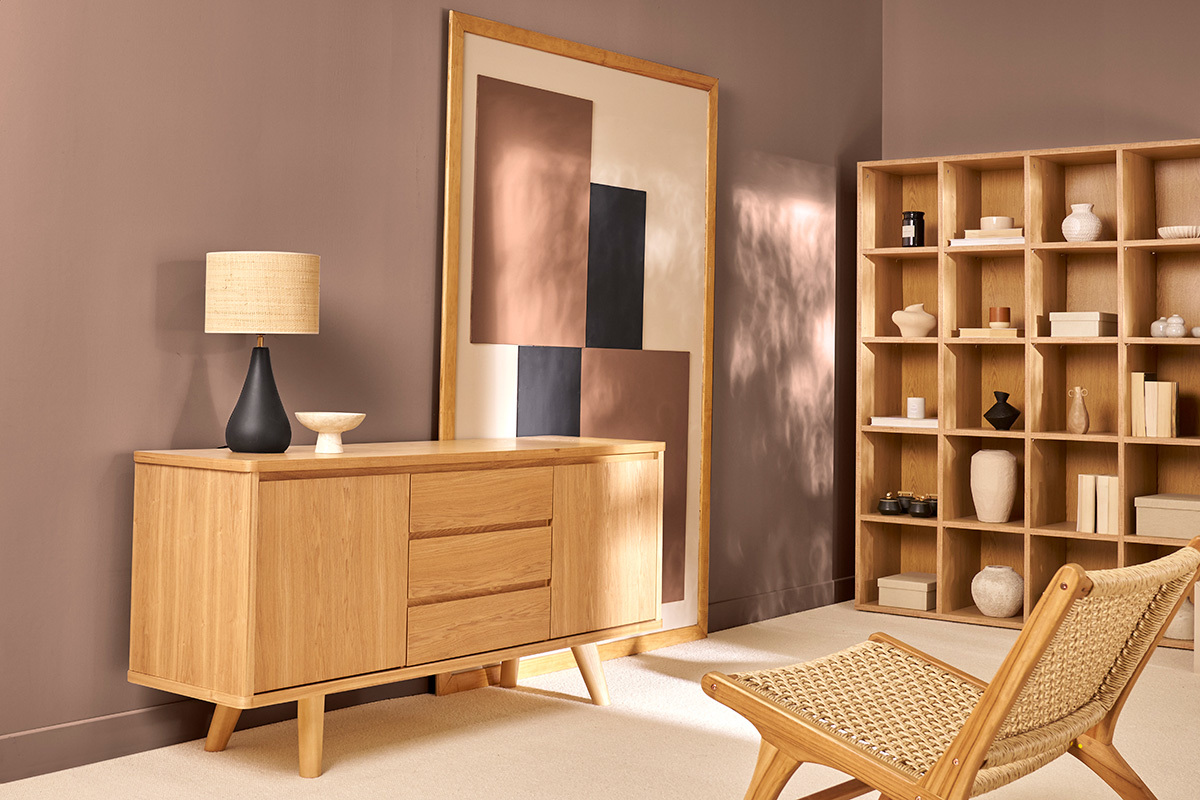 Buffet scandinave en bois clair avec deux portes et trois tiroirs, accompagn� d'autres meubles dans un salon.