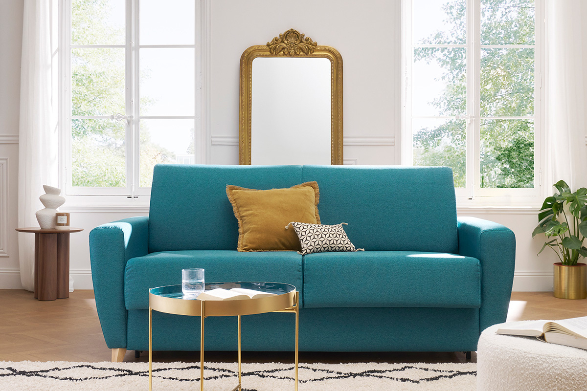 Canap� convertible bleu canard 3 places, vue de face, avec coussins et table basse.