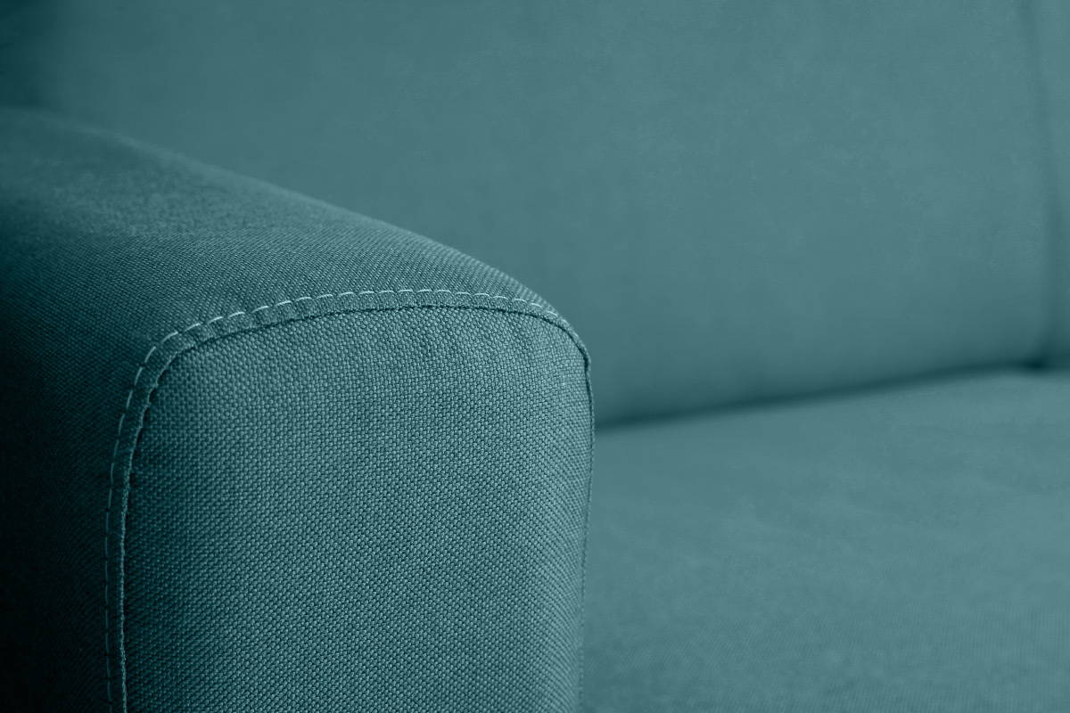 D�tail d'un canap� en tissu bleu canard avec couture visible.