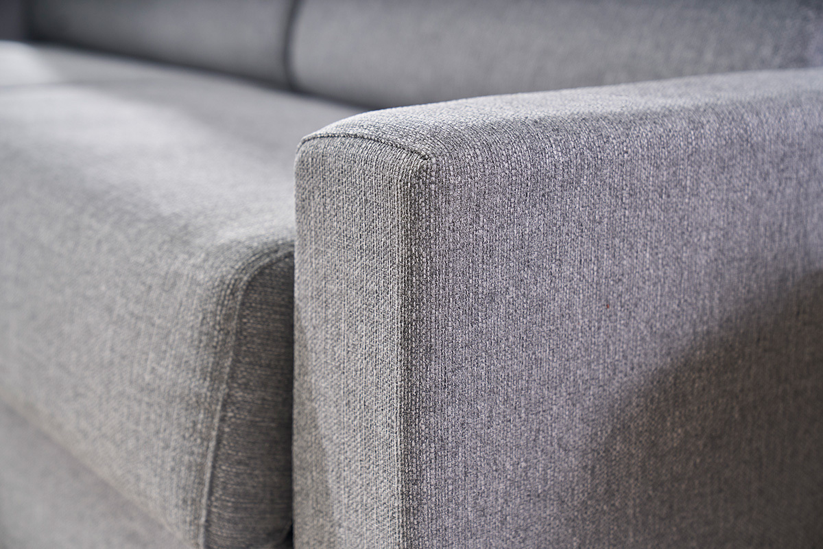 D�tail du accoudoir d'un canap� convertible 3 places en tissu gris clair