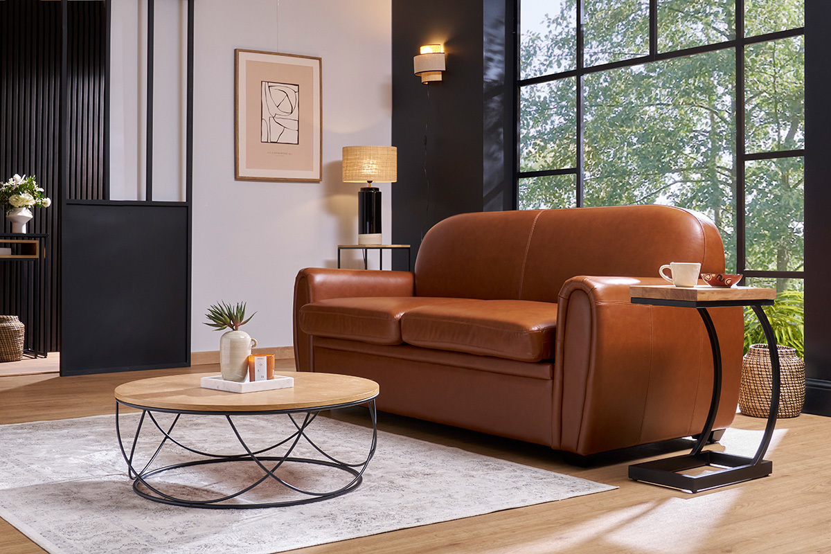 Canap� convertible vintage 3 places en cuir marron, angle 3/4, avec table basse et d�coration.