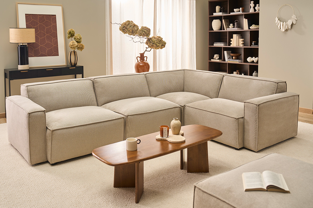 Canap� d'angle modulable 5 places en tissu beige dans un salon moderne.