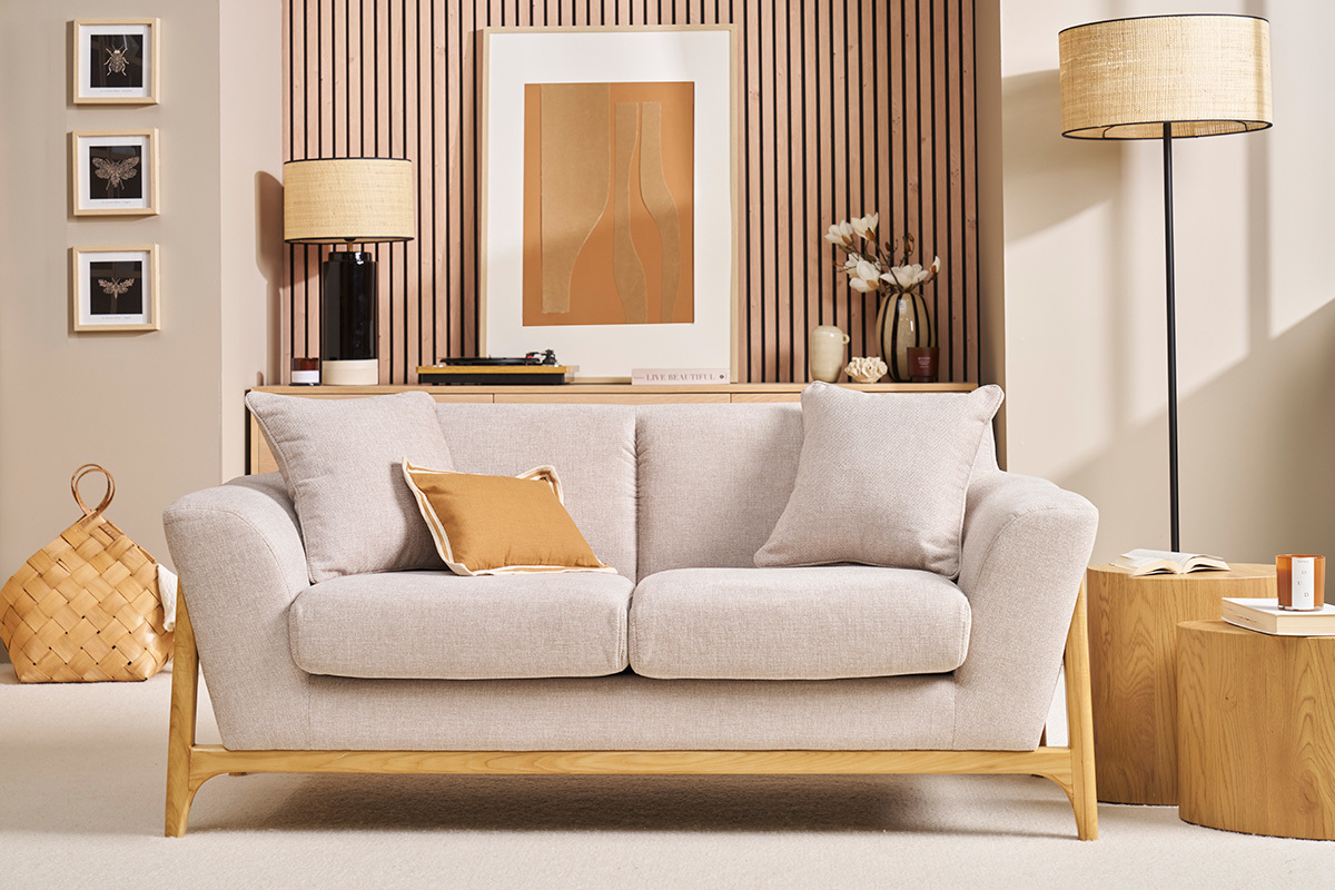 Canap� beige 2 places en tissu velours avec pieds en bois clair, vue de face dans un salon d�cor�.