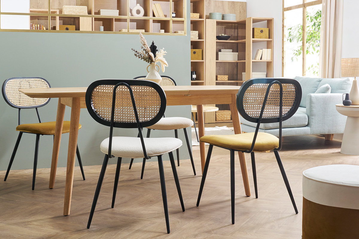 Quatre chaises SWANN autour d'une table en bois, dossier en rotin et assise en velours.