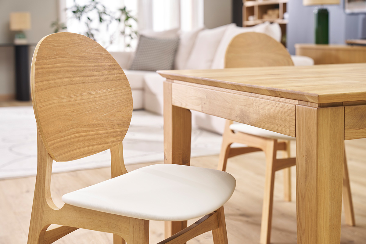 Chaises scandinaves en bois clair et assise blanche avec table en bois clair.
