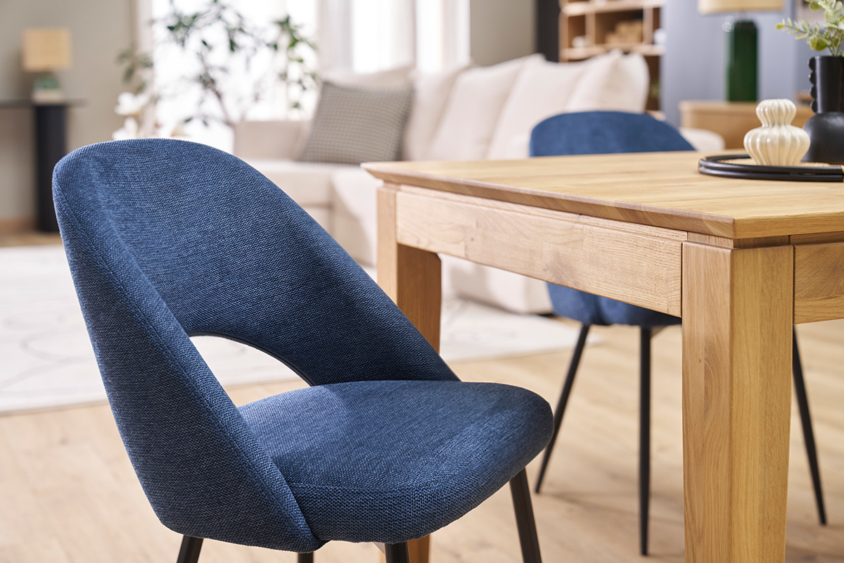 Chaises vintage en tissu bleu avec pieds en m�tal noir pr�s d'une table en bois.