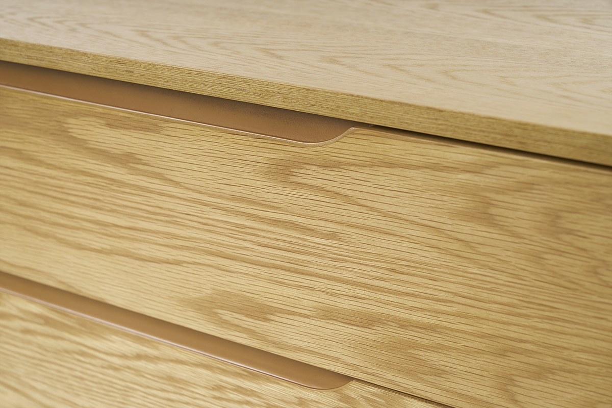 Gros plan de la commode scandinave en bois clair avec poign�es int�gr�es.