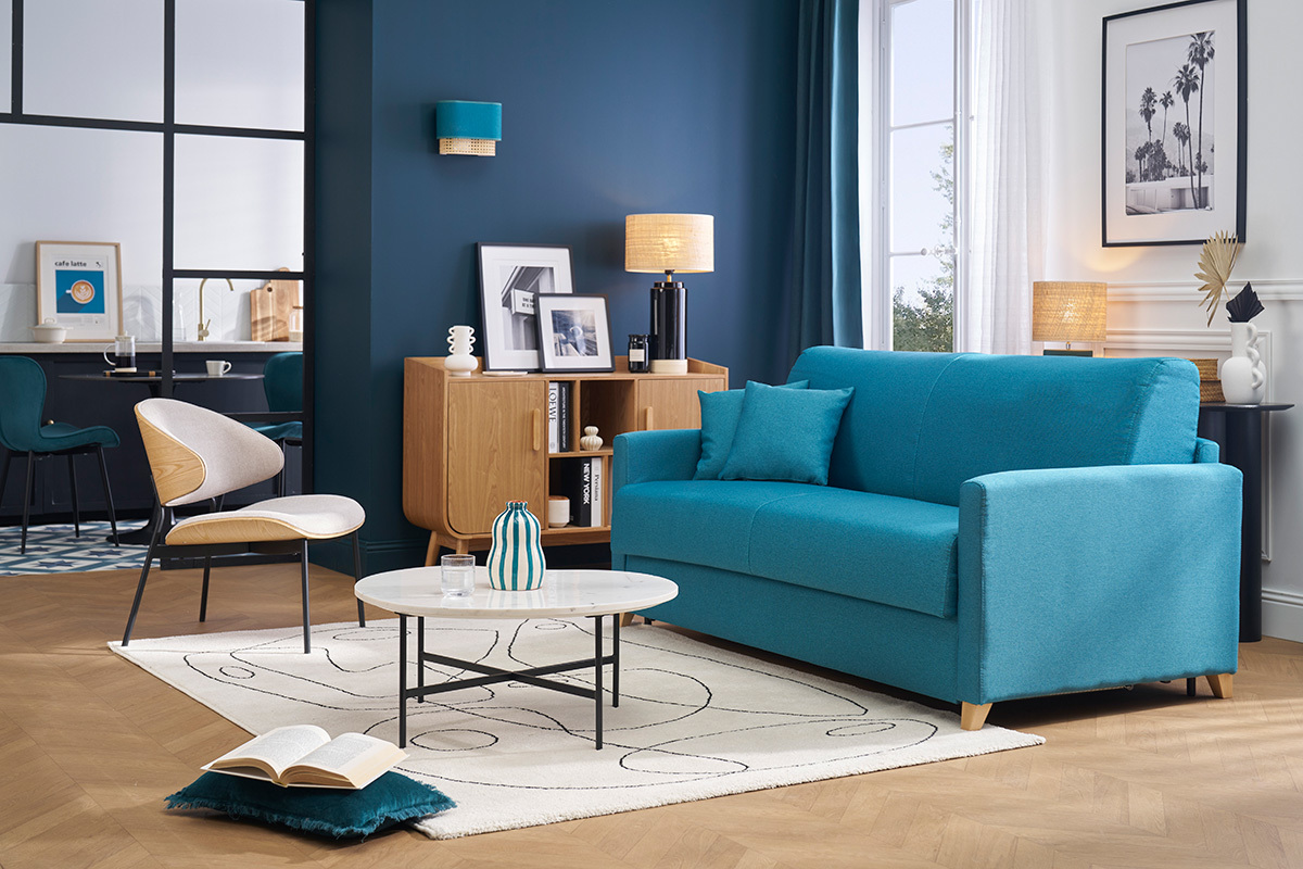 Lampe � poser noire en c�ramique avec abat-jour rabane sur buffet dans salon moderne avec canap� bleu.