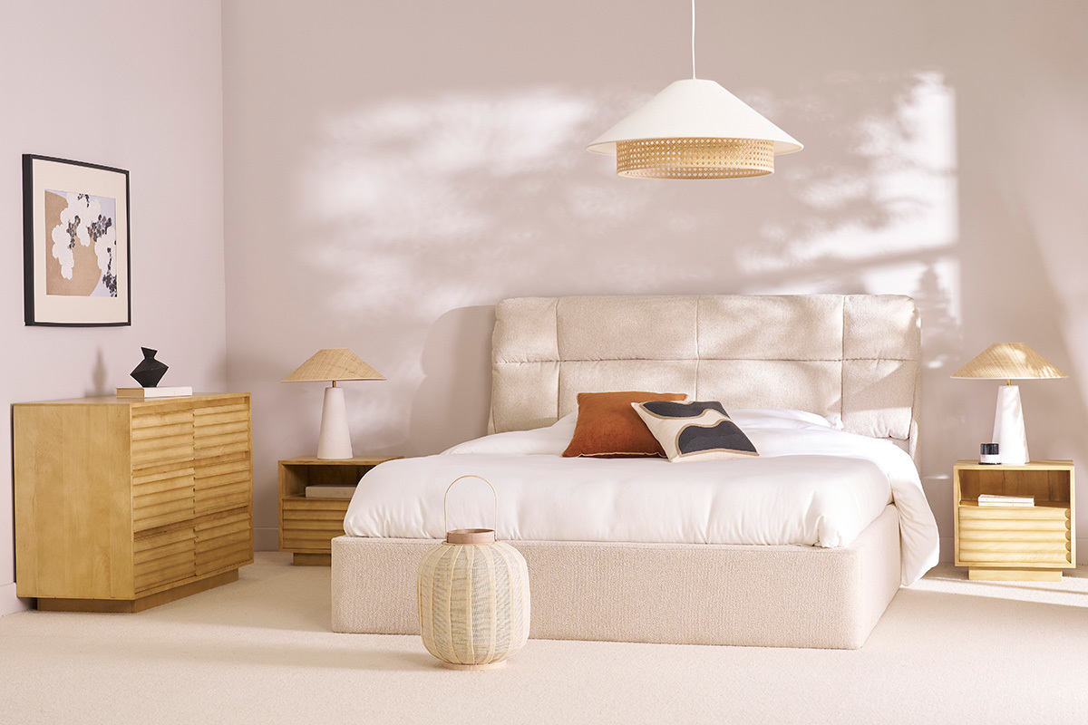 Lit coffre beige 160x200 cm avec t�te de lit rembourr�e, deux tables de chevet, commode et d�corations environnantes.
