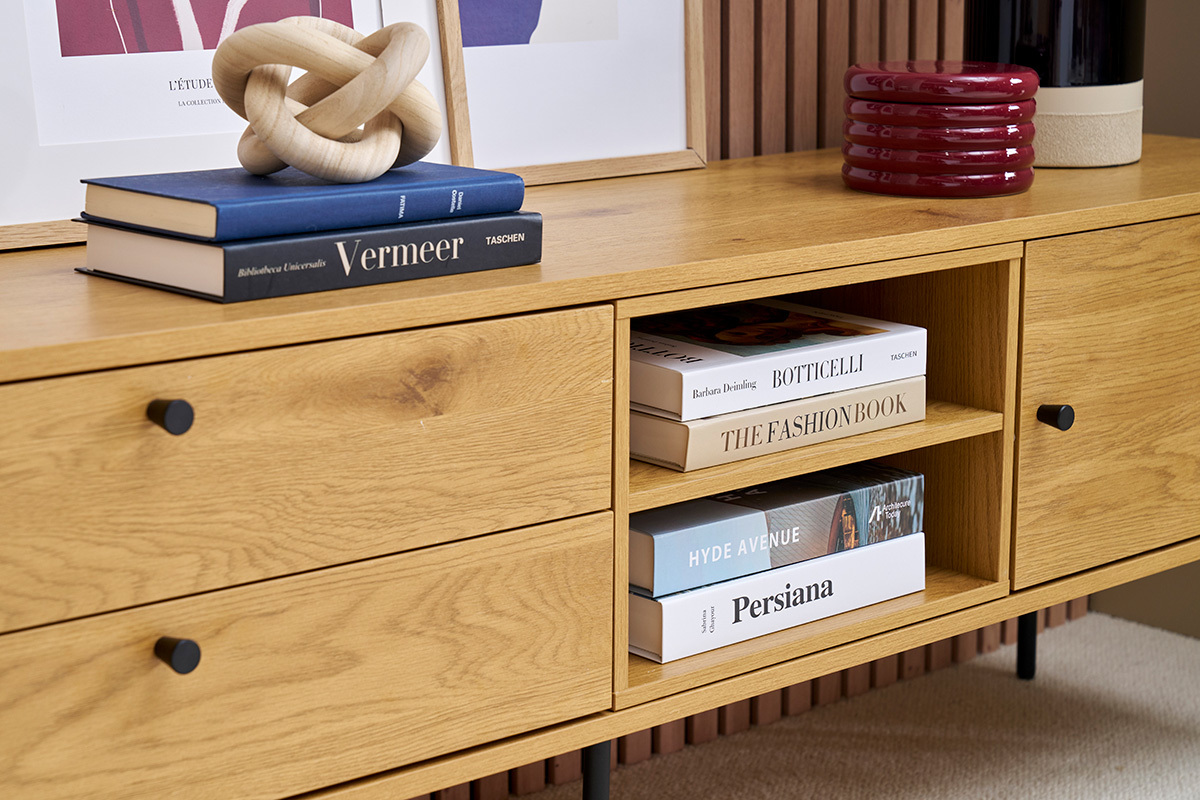 Meuble TV zoom� en bois clair avec livres et objets d�coratifs sur le dessus.