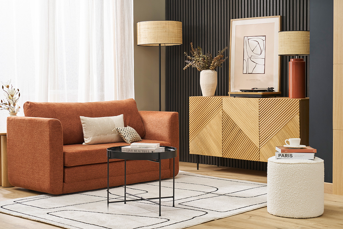 Int�rieur avec canap� terracotta, pouf blanc, table basse et buffet en bois.