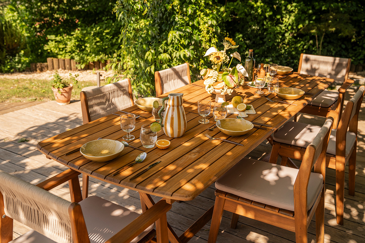 Table de jardin extensible en bois massif, vue de dessus avec assiettes et verres pr�ts pour un repas.