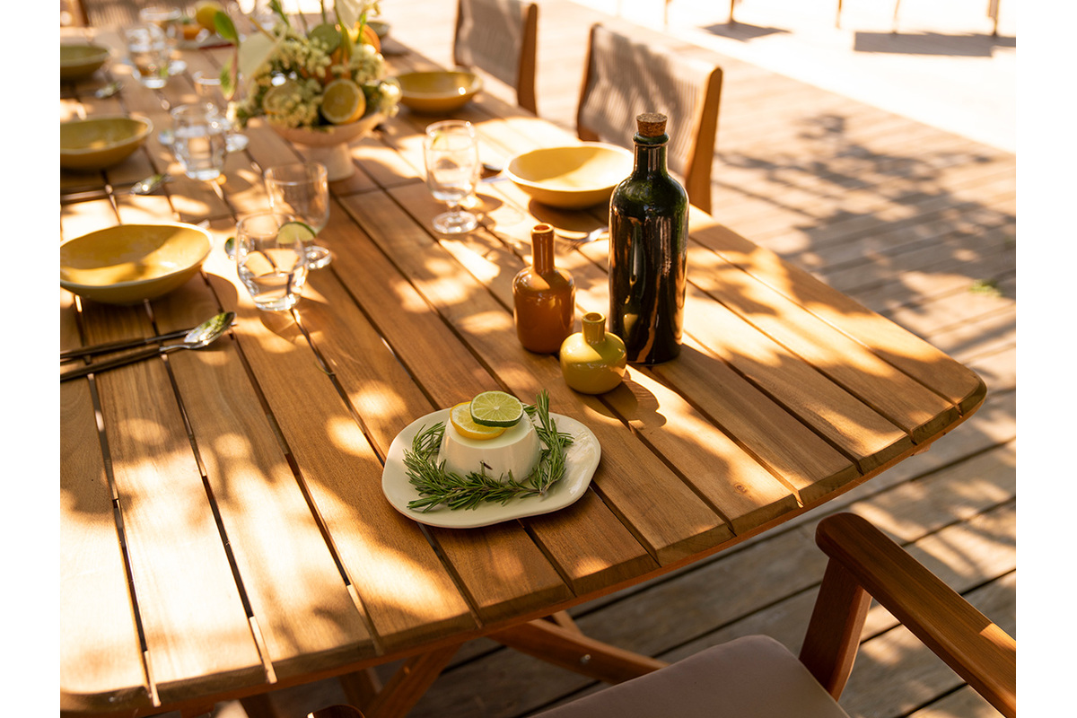 Table de jardin extensible en bois massif, vue de dessus avec assiettes et boissons