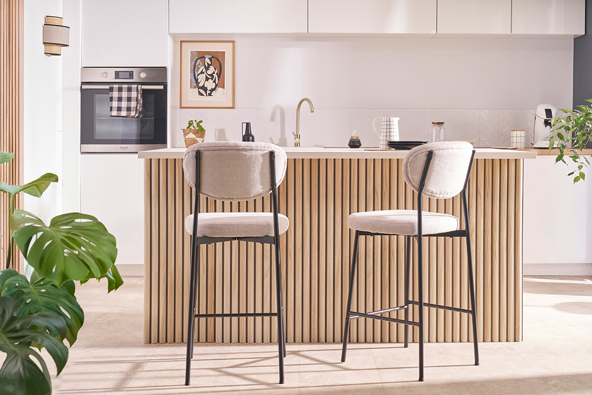 Tabourets de bar BREKA en tissu effet velours beige et pied en m�tal noir, plac�s devant un �lot de cuisine.