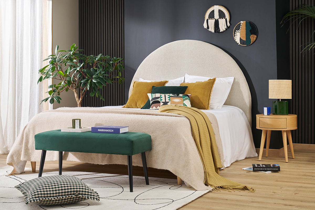 Chambre avec t�te de lit ronde beige, coussins, table d'appoint et d�coration murale.